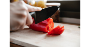 Chopping red bell pepper on board