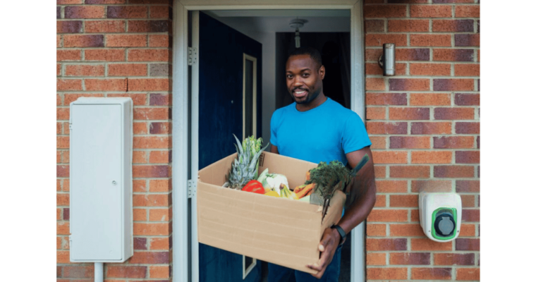 mid adult male holding a cardboard box full of vegetables for delivery