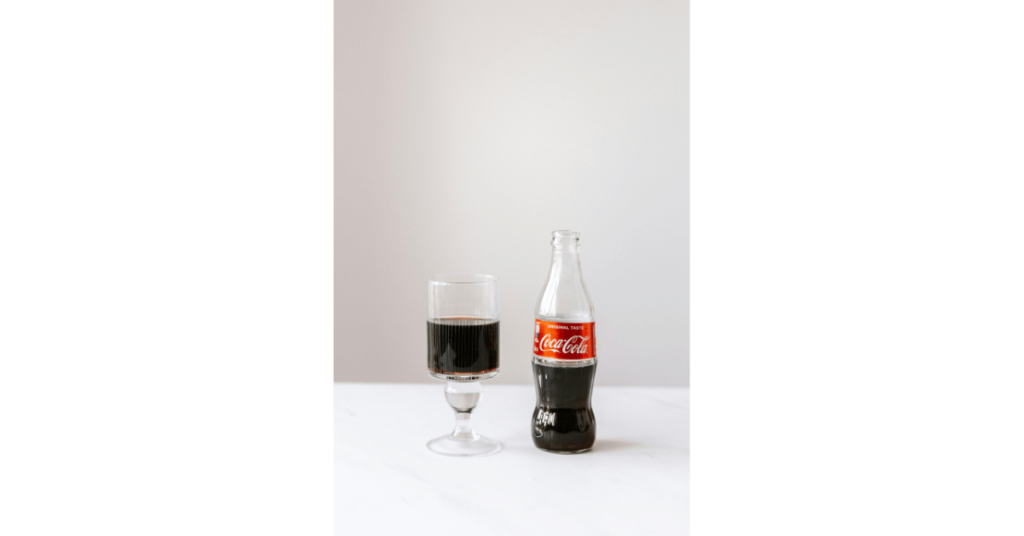 Bottle of Coke and a half filled glass on table