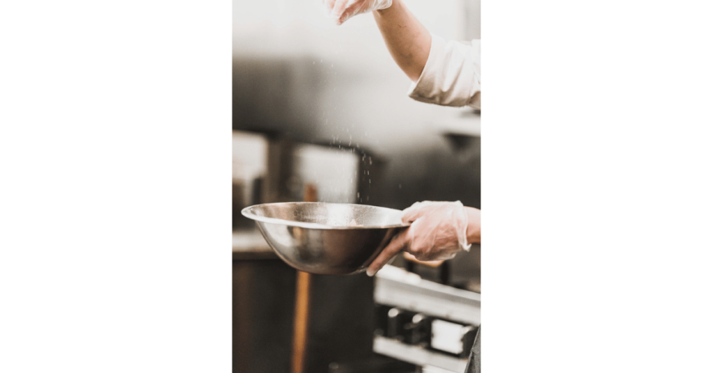 A hand holding an enamel bowl