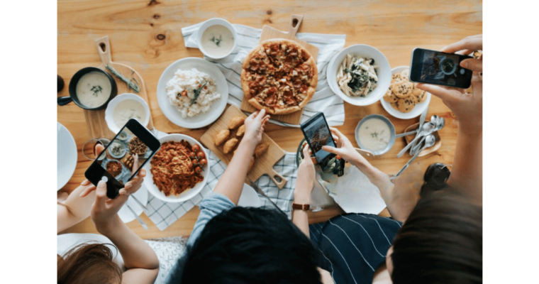 A group of friends taking pictures of food with smartphones
