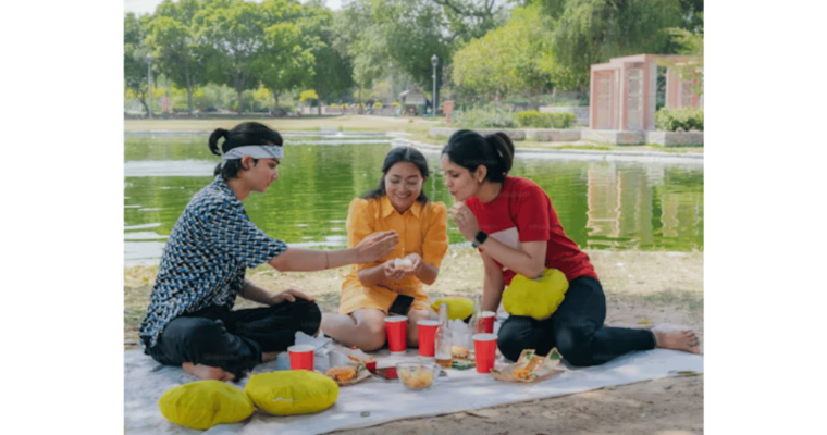 A group of people sitting on a blanket near a body of water. Unsplash/Pramod Tiwari