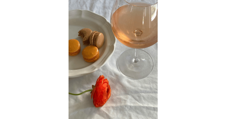 A glass of rose wine placed near sweet macarron