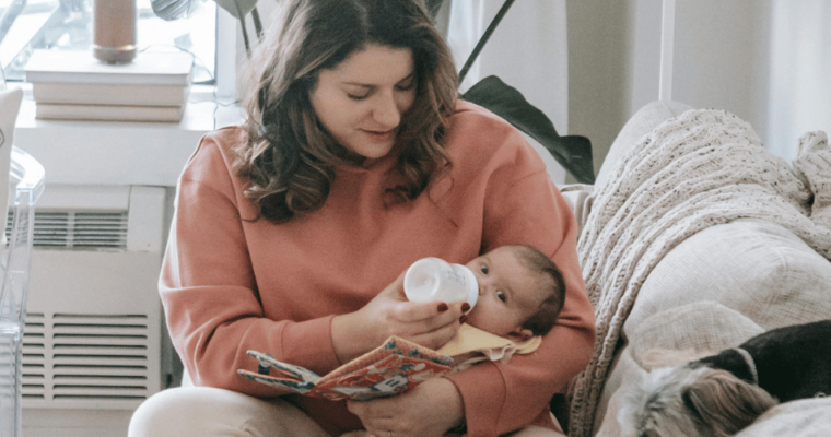 Woman feeding baby on couch in a room