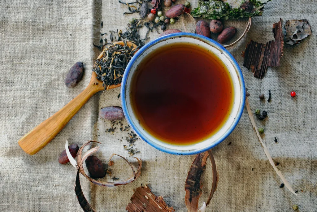 Cup of rooibos on top of a cloth next to rooibos leaves; one of science-backed traditional SA foods.