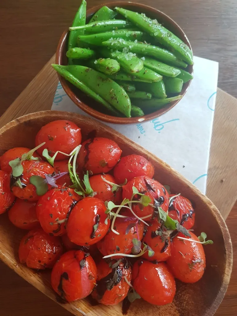 Green beans in a bowl and tomatoes in a separate bowl dish in a vegan restaurant in Pretoria.